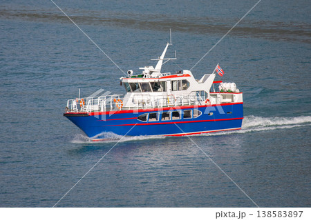 Small blue boat travels on water with a flag while a sunny day offers clear skies and smooth waves Small blue boat travels on water with a flag while a sunny day offers clear skies and smooth waves 138583897