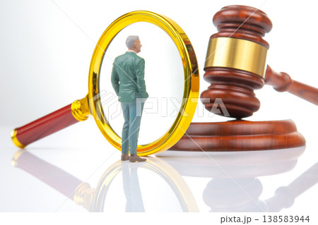 Miniature people examine a magnifying glass next to a gavel in a legal setting during the daytime 138583944