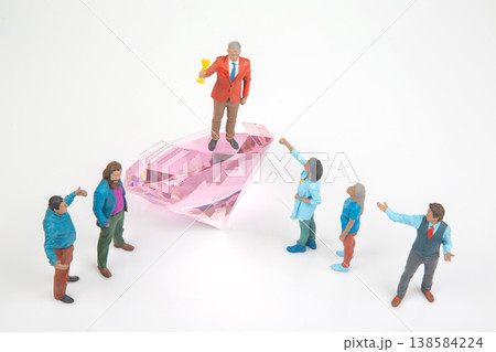 Miniature people celebrate on a giant diamond with one holding a trophy and others cheering  138584224