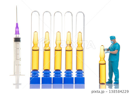 Miniature people working with syringes and vials in a small lab setting during a bright day Miniature people working with syringes and vials in a small lab setting during a bright day 138584229