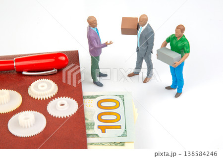 Miniature people discussing money while holding boxes and standing on a table with gears and cash Miniature people discussing money while holding boxes and standing on a table with gears and cash 138584246