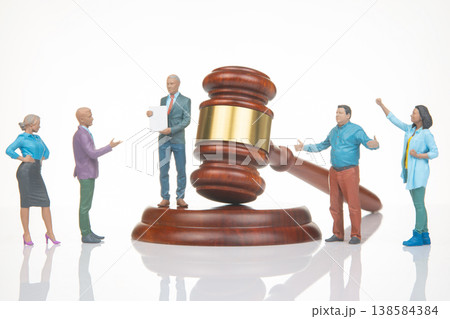 Miniature people holding a meeting around a gavel with a judge standing in front of them showi Miniature people holding a meeting around a gavel with a judge standing in front of them showi 138584384