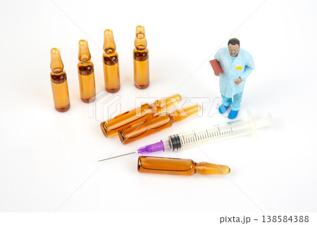 Miniature people gather around syringes and medicine bottles in a small setting showcasing medical Miniature people gather around syringes and medicine bottles in a small setting showcasing medical 138584388