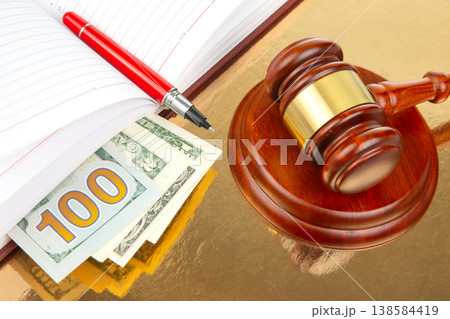 Court gavel rests on golden table near cash, notebook, and pen during legal proceedings Court gavel rests on golden table near cash, notebook, and pen during legal proceedings 138584419