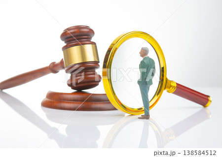 Miniature people standing near a gavel and magnifying glass on a plain background Miniature people standing near a gavel and magnifying glass on a plain background 138584512