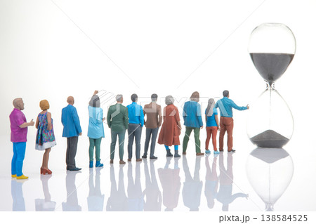 Miniature people gather around an hourglass to watch time pass during a quiet moment 138584525