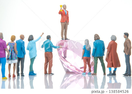 Miniature figures gather around a large gem during a celebration in a simple setting under bright Miniature figures gather around a large gem during a celebration in a simple setting under bright 138584526