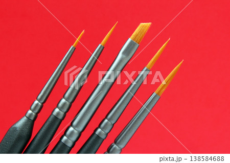 Different types of paintbrushes arranged in a line on a red surface Different types of paintbrushes arranged in a line on a red surface 138584688