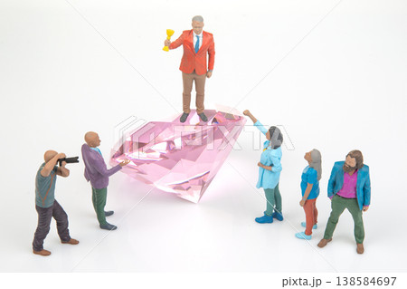 Miniature people celebrating around a large pink diamond during a fun creative scene 138584697