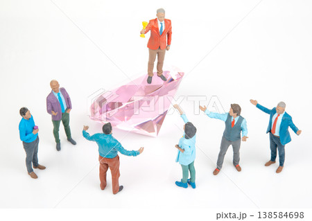 Miniature figurines celebrate victory on a large pink crystal at an event  138584698