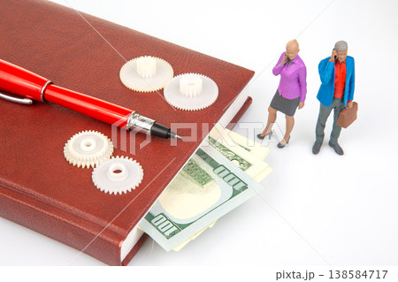 Miniature figurines discussing money and planning next steps on a notebook with a pen Miniature figurines discussing money and planning next steps on a notebook with a pen 138584717