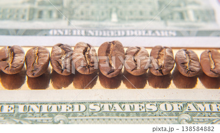 Coffee beans placed on top of a one hundred dollar bill in a simple arrangement on a table 138584882
