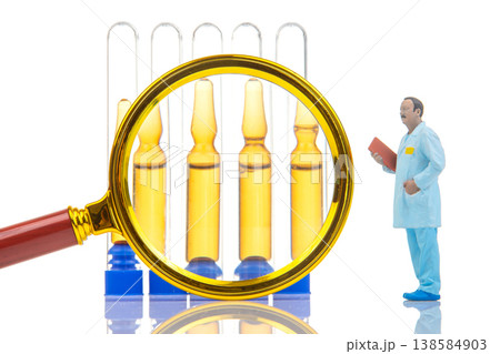 Miniature figurine examines vials with magnifying glass in laboratory setting Miniature figurine examines vials with magnifying glass in laboratory setting 138584903