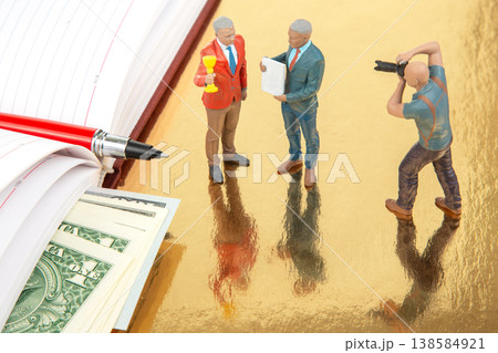 Miniature figurines of people in a business conversation with money on the table and a photographer  138584921