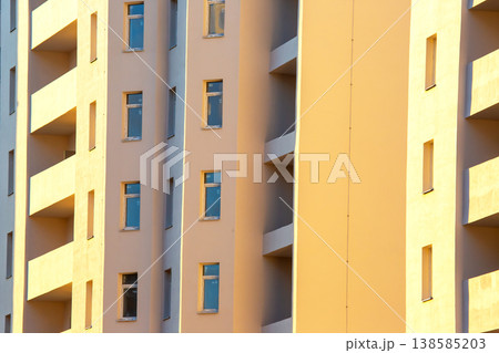 Building with windows in a city during sunset, casting shadows and light 138585203
