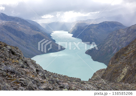 View of a river winding through mountains under cloudy skies in a remote location at midday View of a river winding through mountains under cloudy skies in a remote location at midday 138585206