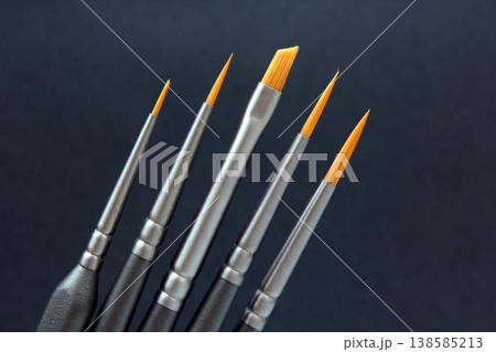 Different sizes of paintbrushes arranged in a row on a dark background showing tools Different sizes of paintbrushes arranged in a row on a dark background showing tools 138585213