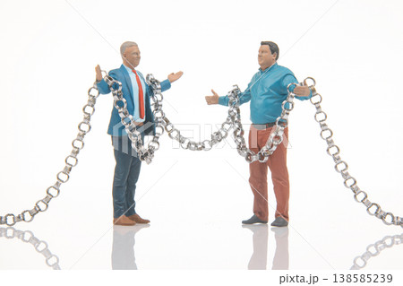 Miniature people holding metal chains in a studio setting during bright daylight 138585239