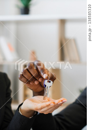 An African American man hands a key to a woman, symbolizing a real estate transaction or new beginning 138585310