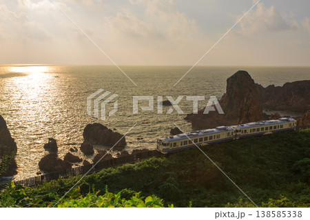 夕日に輝く日本海を背景に五能線の気動車が海岸線を行く 夕日に輝く日本海を背景に五能線の気動車が海岸線を行く 138585338