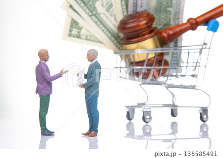 Two figures discuss legal matters with cash and a gavel in a shopping cart on a white background 138585491