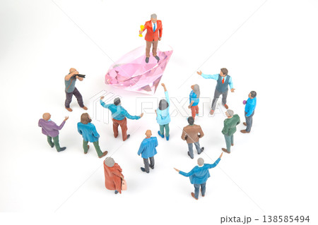 People gather around a man in a suit standing on a gem while others engage in different activities  138585494