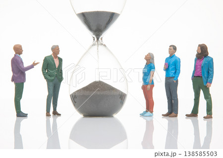 Group of people watching hourglass as sand flows during a creative scene focused on time Group of people watching hourglass as sand flows during a creative scene focused on time 138585503