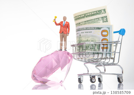 Miniature people celebrate success with money and a gem in a shopping cart during a creative display Miniature people celebrate success with money and a gem in a shopping cart during a creative display 138585709