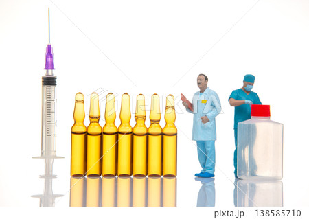 Miniature people engaged in a medical scene with syringes and vials Miniature people engaged in a medical scene with syringes and vials 138585710