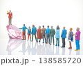Miniature people celebrate around a large diamond-shaped crystal on a white surface during  138585720