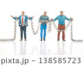 Miniature people hold chains in creative setup showcasing teamwork and cooperation in a unique scene 138585723
