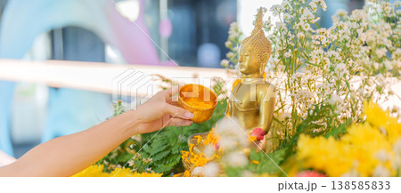 Happy Songkran festival day in Thailand or Thai Happy New Year. hand pouring water on golden Buddha statue with flowers and garland in. Holiday and culture concept Happy Songkran festival day in Thailand or Thai Happy New Year. hand pouring water on golden Buddha statue with flowers and garland in. Holiday and culture concept 138585833