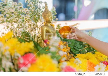 Happy Songkran festival day in Thailand or Thai Happy New Year. hand pouring water on golden Buddha statue with flowers and garland in. Holiday and culture concept Happy Songkran festival day in Thailand or Thai Happy New Year. hand pouring water on golden Buddha statue with flowers and garland in. Holiday and culture concept 138585834