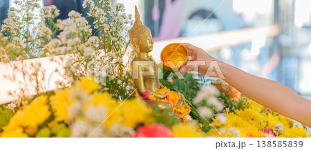 Happy Songkran festival day in Thailand or Thai Happy New Year. hand pouring water on golden Buddha statue with flowers and garland in. Holiday and culture concept Happy Songkran festival day in Thailand or Thai Happy New Year. hand pouring water on golden Buddha statue with flowers and garland in. Holiday and culture concept 138585839