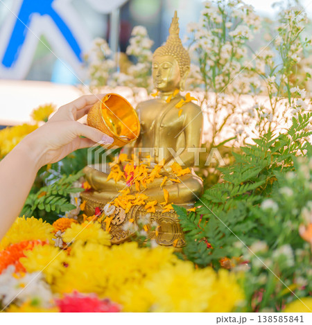 Happy Songkran festival day in Thailand or Thai Happy New Year. hand pouring water on golden Buddha statue with flowers and garland in. Holiday and culture concept Happy Songkran festival day in Thailand or Thai Happy New Year. hand pouring water on golden Buddha statue with flowers and garland in. Holiday and culture concept 138585841