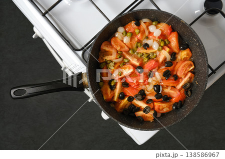 Cooking tomatoes and vegetables in a pan on a stove during the day Cooking tomatoes and vegetables in a pan on a stove during the day 138586967