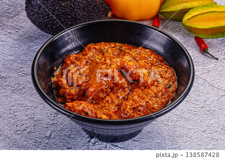 Indian butter chicken masala, a spicy traditional curry served in a bowl on a textured background. 138587428