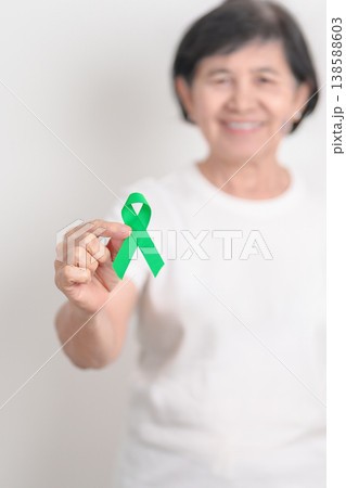 Elderly with Green Ribbon for concept of April Donate Life month, Organ Donation and Transplant Awareness, May Mental Health Awareness month and October Liver cancer. Health and world cancer day 138588603