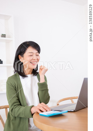 計算をしながらガッツポーズをする50代主婦 138589129