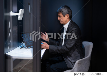 個室ポッドを利用してビデオ会議で説明を行う会社員の男性 138590066