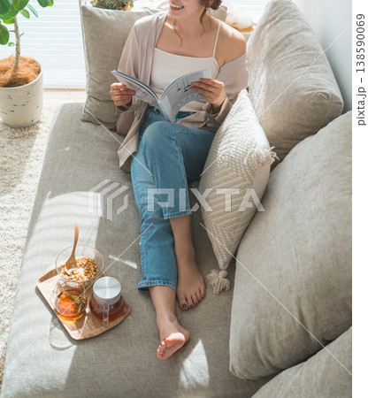 リビングのソファーに座りティータイムに雑誌を読むオシャレなアジア人女性 リビングのソファーに座りティータイムに雑誌を読むオシャレなアジア人女性 138590069