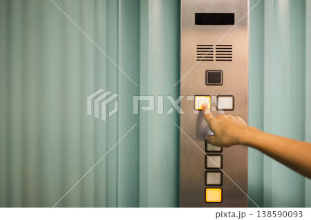 Close up of a hand pressing button on elevator control panel. 138590093