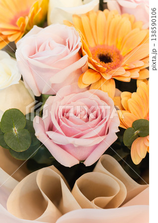 Elegant pastel bouquet of pink roses and orange gerbera with soft wrapping in vertical. 138590106