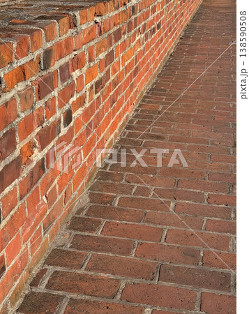 Close view of red brick wall and paved walkway at Malbork Castle in Poland showing texture and pattern in sunlight. Architecture, texture and construction concept 138590508