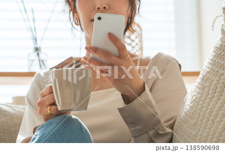 リビングのソファに座りスマホを見るアジア人女性 リビングのソファに座りスマホを見るアジア人女性 138590698