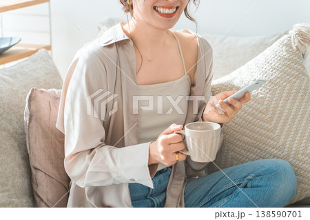 リビングのソファに座りスマホを見るアジア人女性 138590701