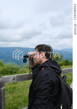 Hiker Looks Through Monocular at Mountains 138590952