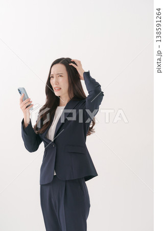 困った表情でスマホを持つスーツの女性 138591264