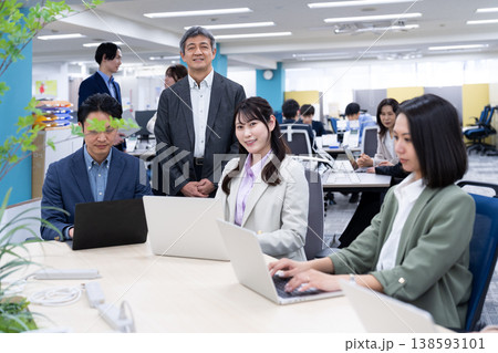 フリーアドレスの職場でコミュニケーションをとる会社員の男女 フリーアドレスの職場でコミュニケーションをとる会社員の男女 138593101