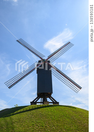 Traditional windmill on grassy hill under blue sky Traditional windmill on grassy hill under blue sky 138593181